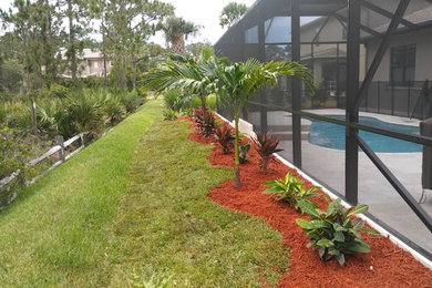 This is an example of a large tropical partial sun backyard mulch landscaping in Miami for summer.