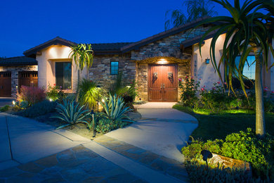 Imagen de acceso privado de estilo americano grande en verano en patio delantero con exposición parcial al sol y adoquines de piedra natural