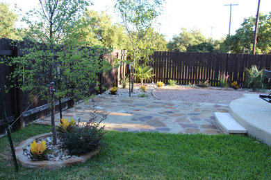 This is an example of a mid-sized traditional shade backyard stone landscaping in Austin for summer.