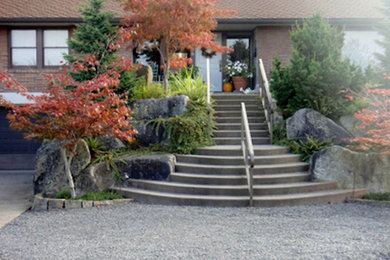 Modelo de jardín clásico de tamaño medio en primavera en patio delantero con jardín francés, exposición total al sol y adoquines de piedra natural
