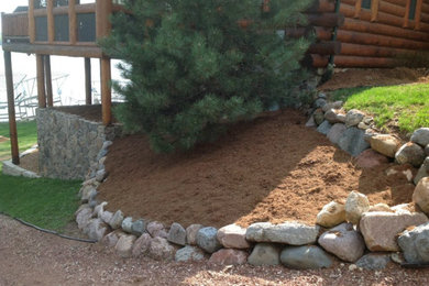 This is an example of a mid-sized shade hillside mulch retaining wall landscape in Milwaukee.