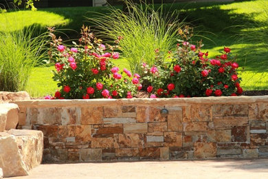 Ejemplo de jardín grande con muro de contención, exposición parcial al sol y adoquines de piedra natural