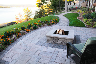 Photo of a mid-sized contemporary partial sun backyard stone landscaping in Ottawa with a fire pit for summer.