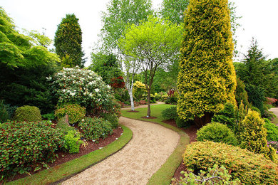 Modelo de camino de jardín tradicional grande en primavera en patio trasero con exposición total al sol y gravilla