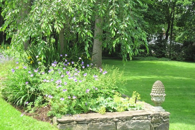 Modelo de jardín tradicional renovado grande en patio trasero con exposición parcial al sol, mantillo y muro de contención