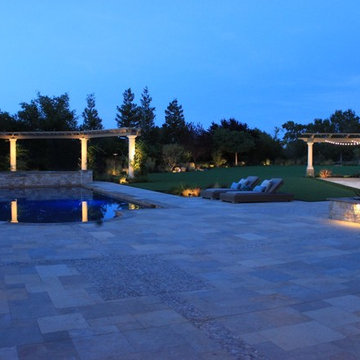Large pool- patio and bocci court at dusk