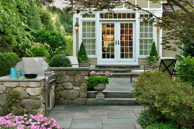 Cette photo montre un jardin arrière chic de taille moyenne avec un foyer extérieur, une exposition partiellement ombragée et des pavés en pierre naturelle.