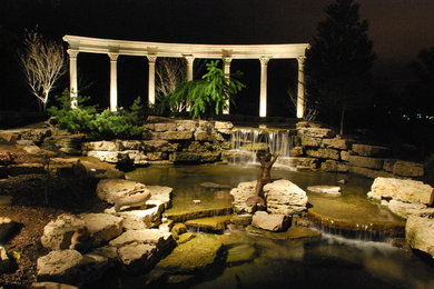 Lighting On A Large Koi Pond And Water Fall