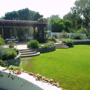 Mediterraner Garten hinter dem Haus mit Kamin, direkter Sonneneinstrahlung und Natursteinplatten in San Diego