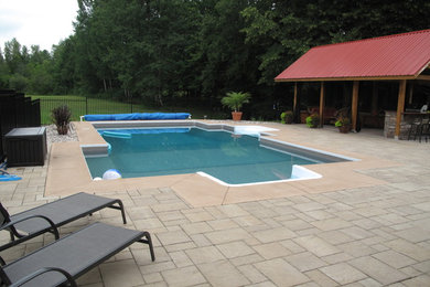 Example of a large minimalist backyard concrete paver pool design in Ottawa