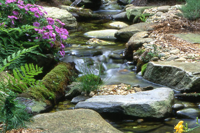 Foto de jardín tradicional en verano con fuente, exposición parcial al sol y adoquines de piedra natural