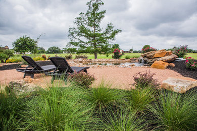 Modelo de jardín de secano clásico renovado de tamaño medio en primavera en patio trasero con brasero, exposición total al sol y gravilla