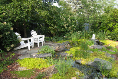 This is an example of a huge eclectic full sun backyard mulch water fountain landscape in Omaha for summer.