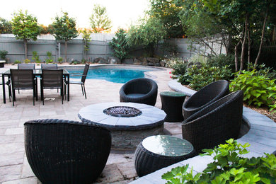 This is an example of a mid-sized contemporary backyard stone landscaping in Ottawa with a fire pit for summer.