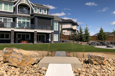 Photo of a large coastal backyard concrete paver landscaping in Calgary with a fire pit.
