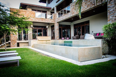 Photo of a large modern back partial sun garden in Miami with natural stone paving.