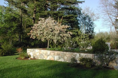 Aménagement d'un jardin arrière contemporain de taille moyenne avec un mur de soutènement, une exposition ensoleillée et des pavés en pierre naturelle.