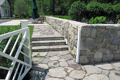 This is an example of a partial sun backyard stone retaining wall landscape in New York.