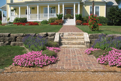 Esempio di un giardino country esposto in pieno sole di medie dimensioni e davanti casa con un muro di contenimento e pavimentazioni in mattoni