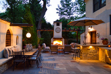 Large tuscan backyard stone patio photo in Chicago with a fireplace