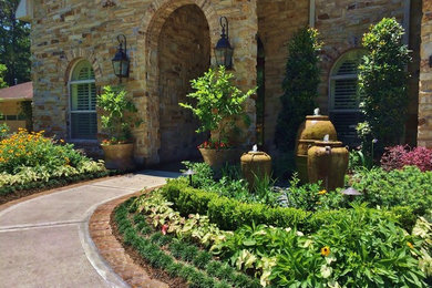 Cette image montre un jardin à la française avant traditionnel de taille moyenne et l'été avec un point d'eau, une exposition ensoleillée et des pavés en brique.