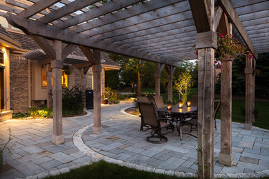 Photo of a large traditional back patio in Milwaukee with natural stone paving.