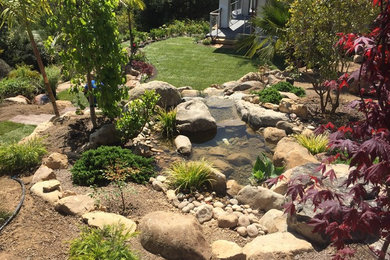 Large world-inspired back garden in Santa Barbara with a water feature and natural stone paving.