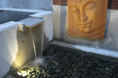 Photo of a small mid-century modern partial sun backyard water fountain landscape in Seattle.