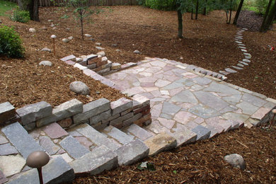 This is an example of a large traditional partial sun and drought-tolerant backyard stone retaining wall landscape in Minneapolis.