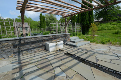Modelo de jardín rural extra grande en verano en patio trasero con jardín francés, fuente, exposición total al sol y adoquines de piedra natural