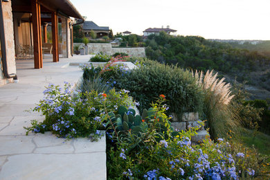 Inspiration for a mid-sized rustic drought-tolerant and full sun backyard stone landscaping in Austin.