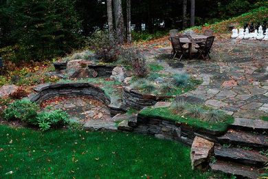 Modelo de jardín grande en patio trasero con muro de contención y adoquines de piedra natural
