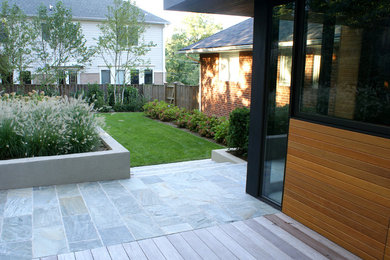 This is an example of a contemporary back garden in DC Metro with natural stone paving.