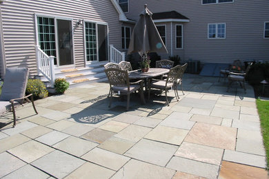 Patio - large modern backyard stone patio idea in Boston
