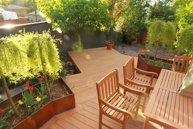 На фото: летний участок и сад среднего размера на заднем дворе в современном стиле с полуденной тенью и настилом с