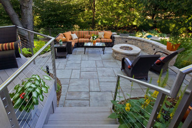 Idée de décoration pour un jardin arrière design avec un foyer extérieur et des pavés en béton.