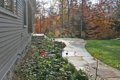 Imagen de camino de jardín clásico grande en verano en patio delantero con exposición total al sol y adoquines de piedra natural