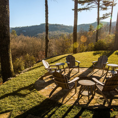 Inspiration for a mid-sized rustic full sun backyard stone landscaping in Other with a fire pit.
