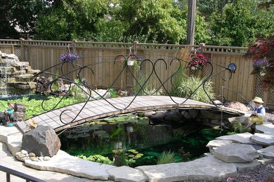 Modelo de jardín tradicional grande en patio trasero con estanque y adoquines de ladrillo