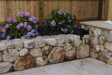 Photo of a mid-sized transitional full sun backyard stone landscaping in Boston for spring.