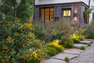 Ejemplo de jardín de estilo de casa de campo pequeño en patio delantero con parterre de flores, exposición total al sol y adoquines de piedra natural