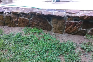 This is an example of a mid-sized contemporary full sun retaining wall landscape in Other.