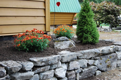 Imagen de jardín tradicional en primavera en patio trasero con muro de contención