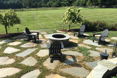 This is an example of a large classic back full sun garden in Philadelphia with a fire feature and natural stone paving.