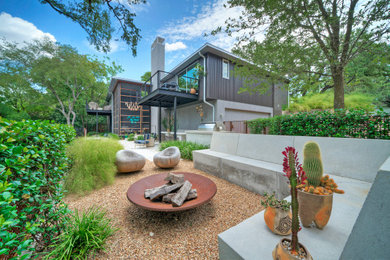 This is an example of a large contemporary drought-tolerant, rock and shade backyard stone landscaping in Austin for spring.