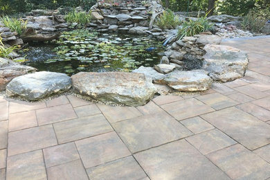 Ejemplo de jardín tradicional grande en patio trasero con estanque, adoquines de piedra natural y exposición total al sol