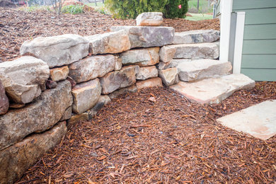 This is an example of a mid-sized traditional partial sun backyard stone landscaping in Other.