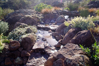 Photo of a mid-sized traditional backyard stone water fountain landscape in San Francisco.