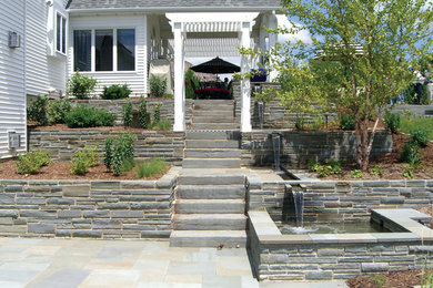 Ejemplo de jardín de estilo americano en patio trasero con fuente y adoquines de piedra natural