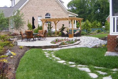 Photo of a large transitional partial sun backyard stone retaining wall landscape in Other for summer.